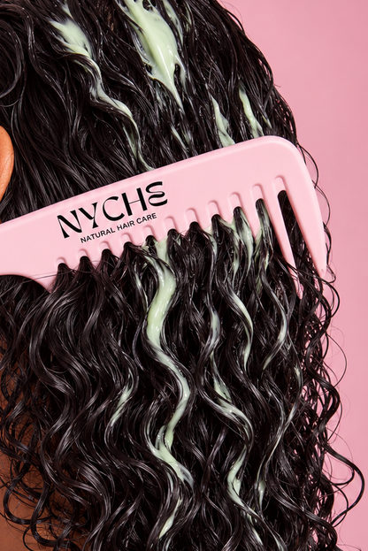 Leave-in detangling hair milk on dark wavy hair, brushed with a pink comb.