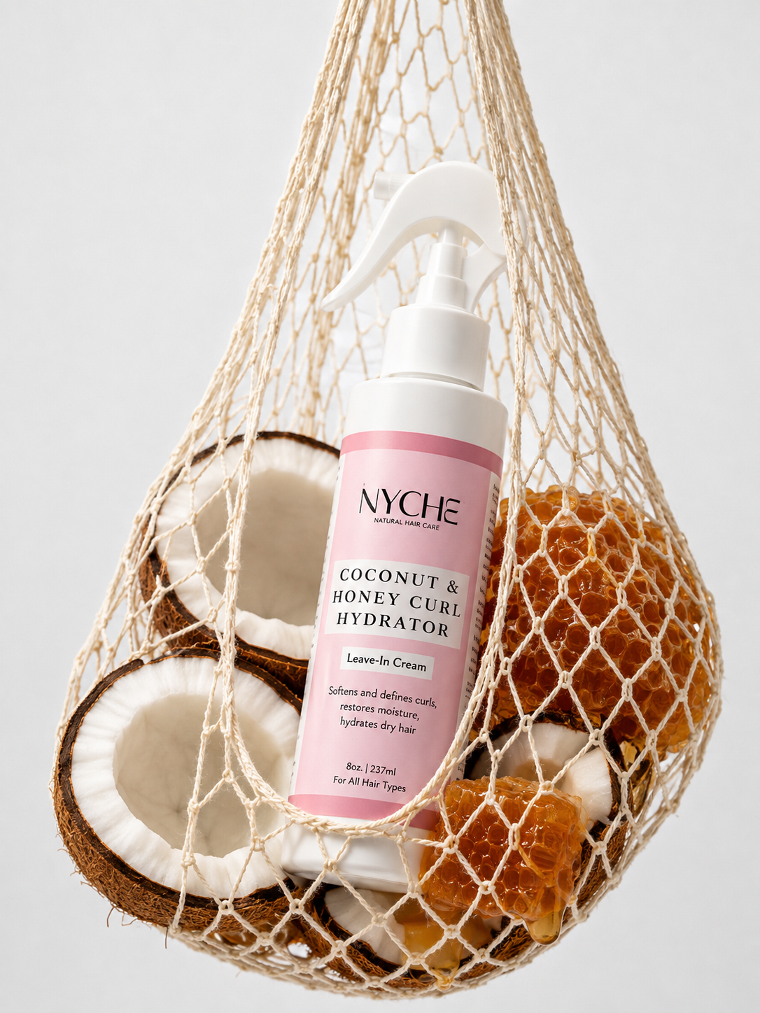 Coconut & Honey Curl Hydrator bottle in hanging net with coconuts and honeycomb
